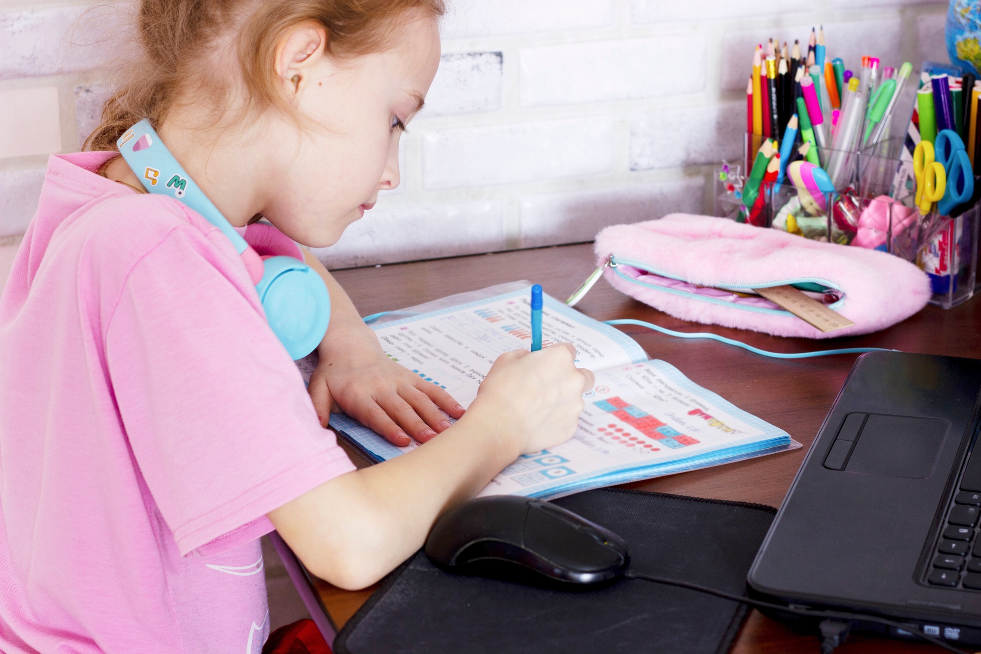 child writes a task in a notebook