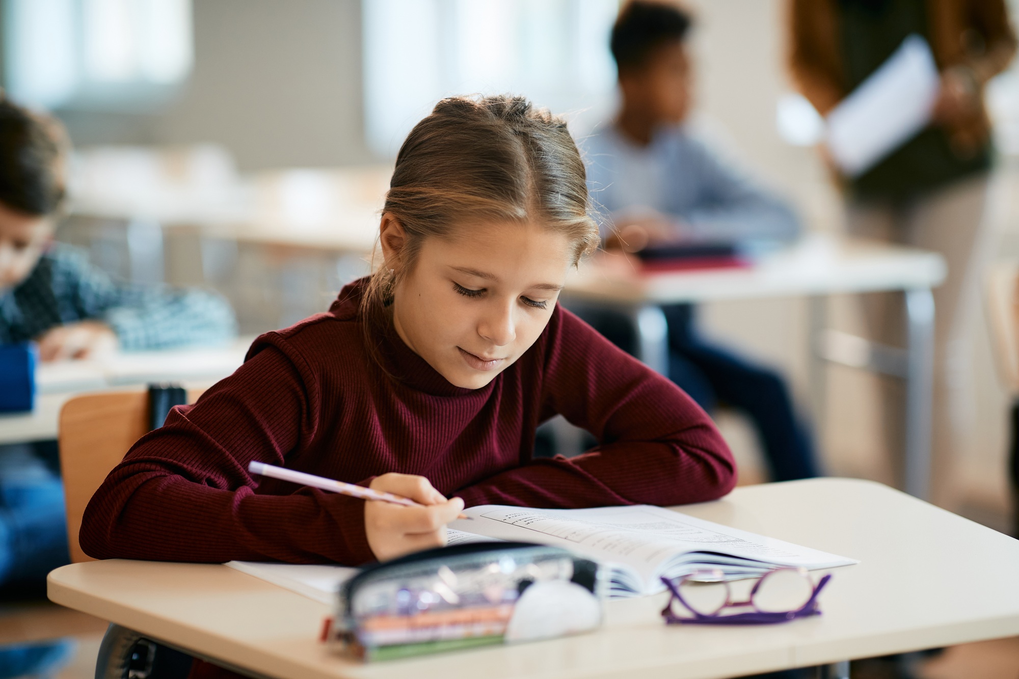 Schoolgirl writing in notebook during a class in the classroom.