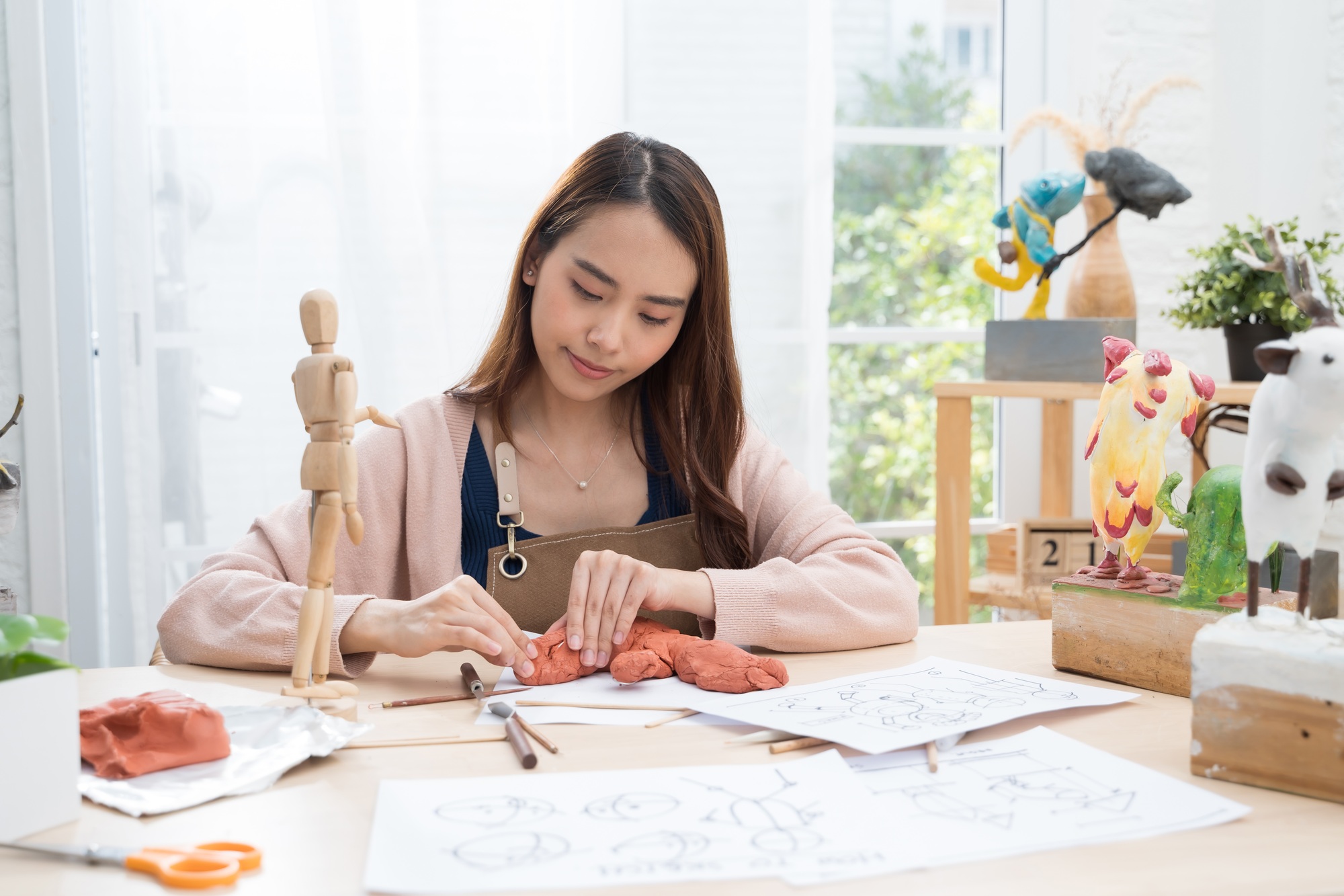 Young Asian girl making a sculpture with modeling clay at home .hobby clay sculpt concept