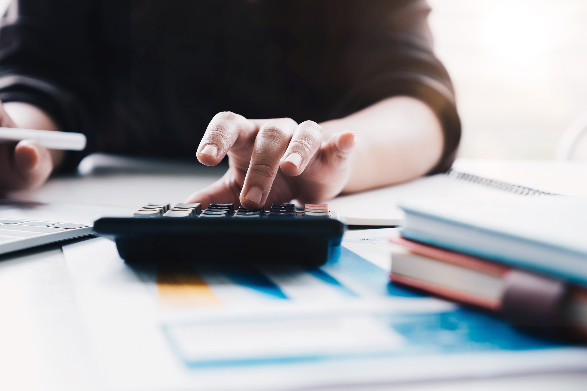 Close up Business woman using calculator and laptop for do math finance