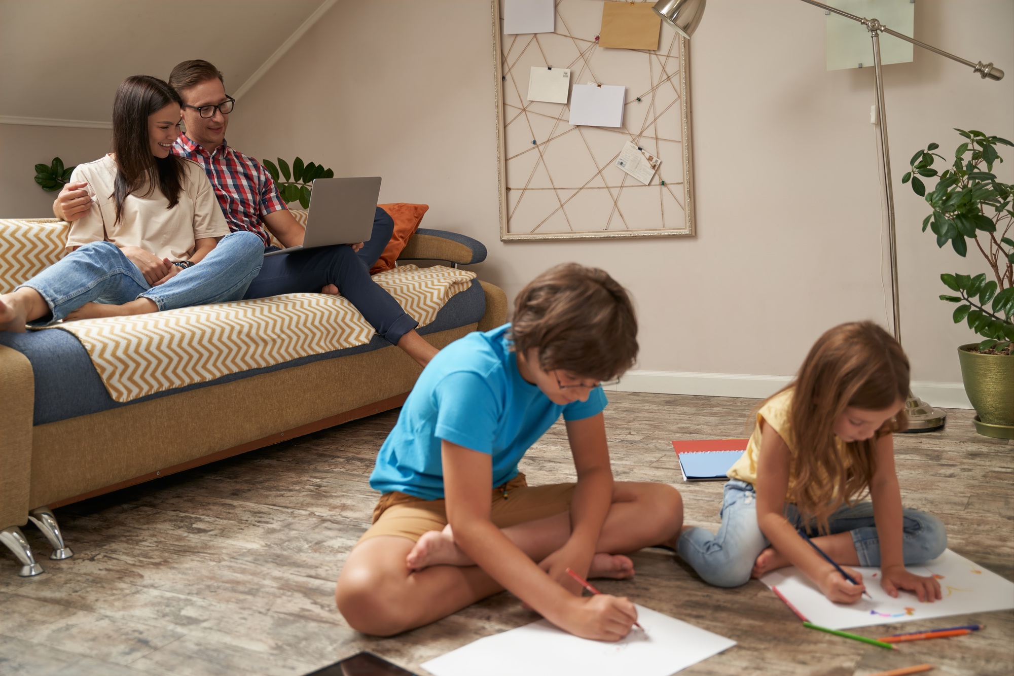 Little boy and girl sitting on the wooden floor and drawing with colorful pencils while
