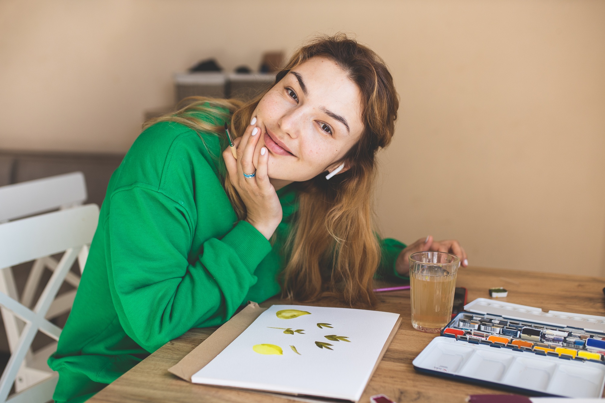 The girl paints with watercolor paints. The process of drawing. The girl is engaged in creativity.