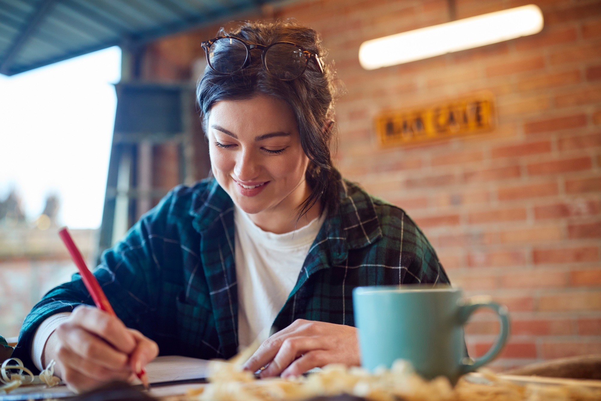 Young Female Carpenter Drawing And Measuring Woodwork Design In Garage Workshop