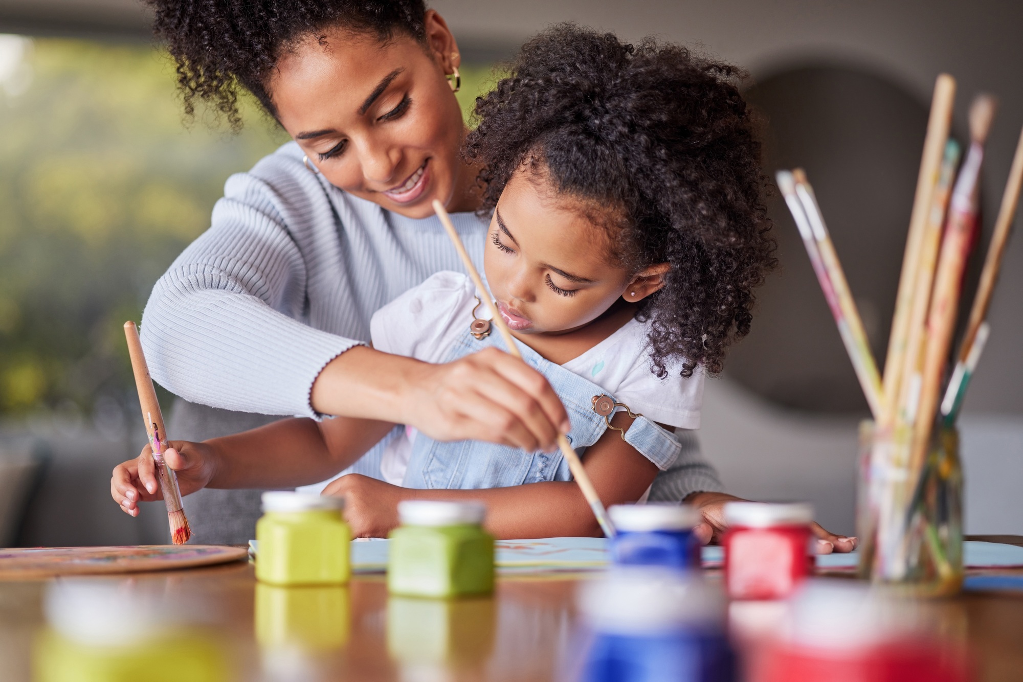 Art, happy mother and child painting for an art preschool project with a young mom helping her daug