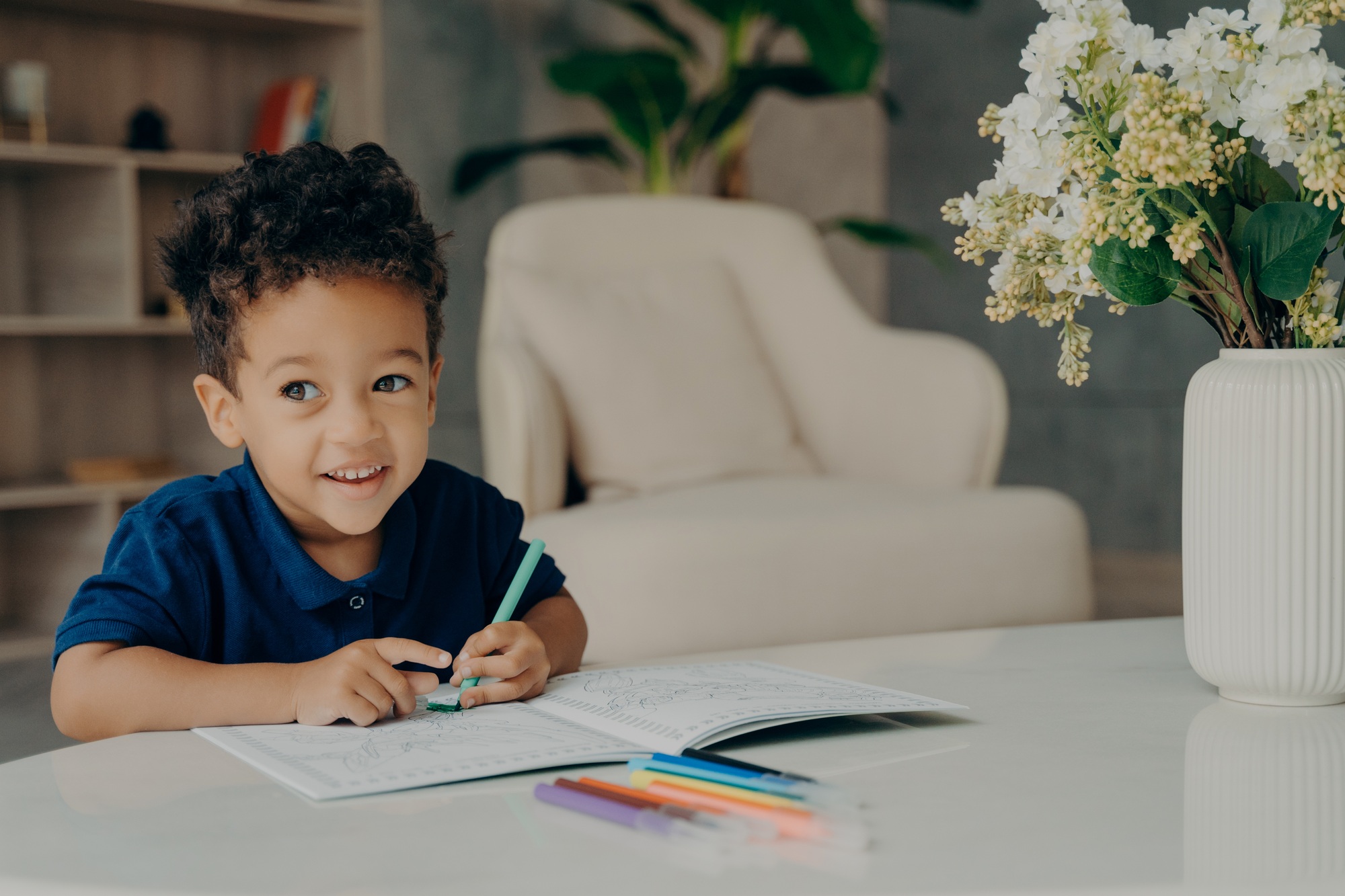 Cute afro american child painting in coloring book at home