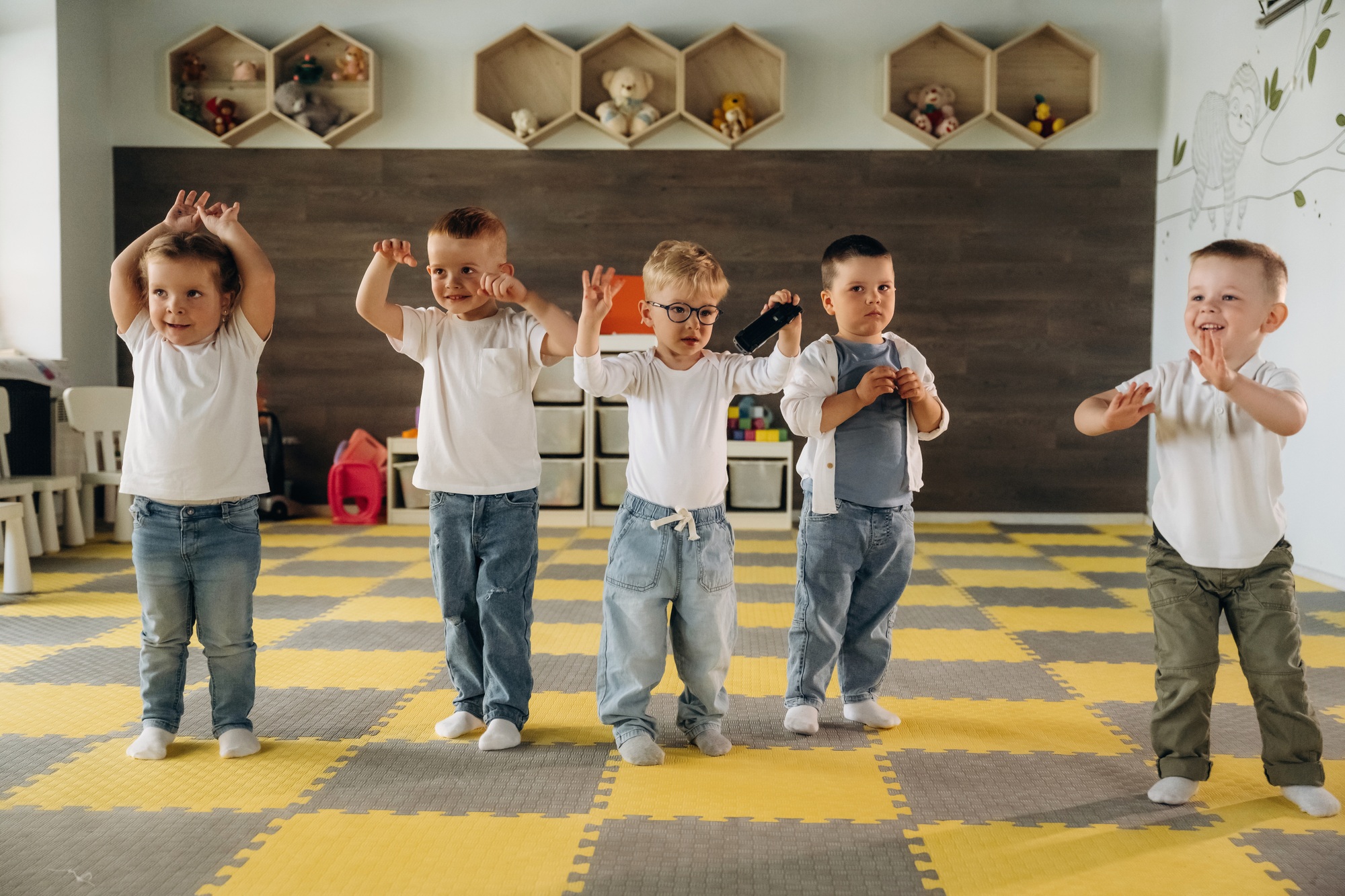 Hands up, standing having fun. Group of children are in the kindergarten