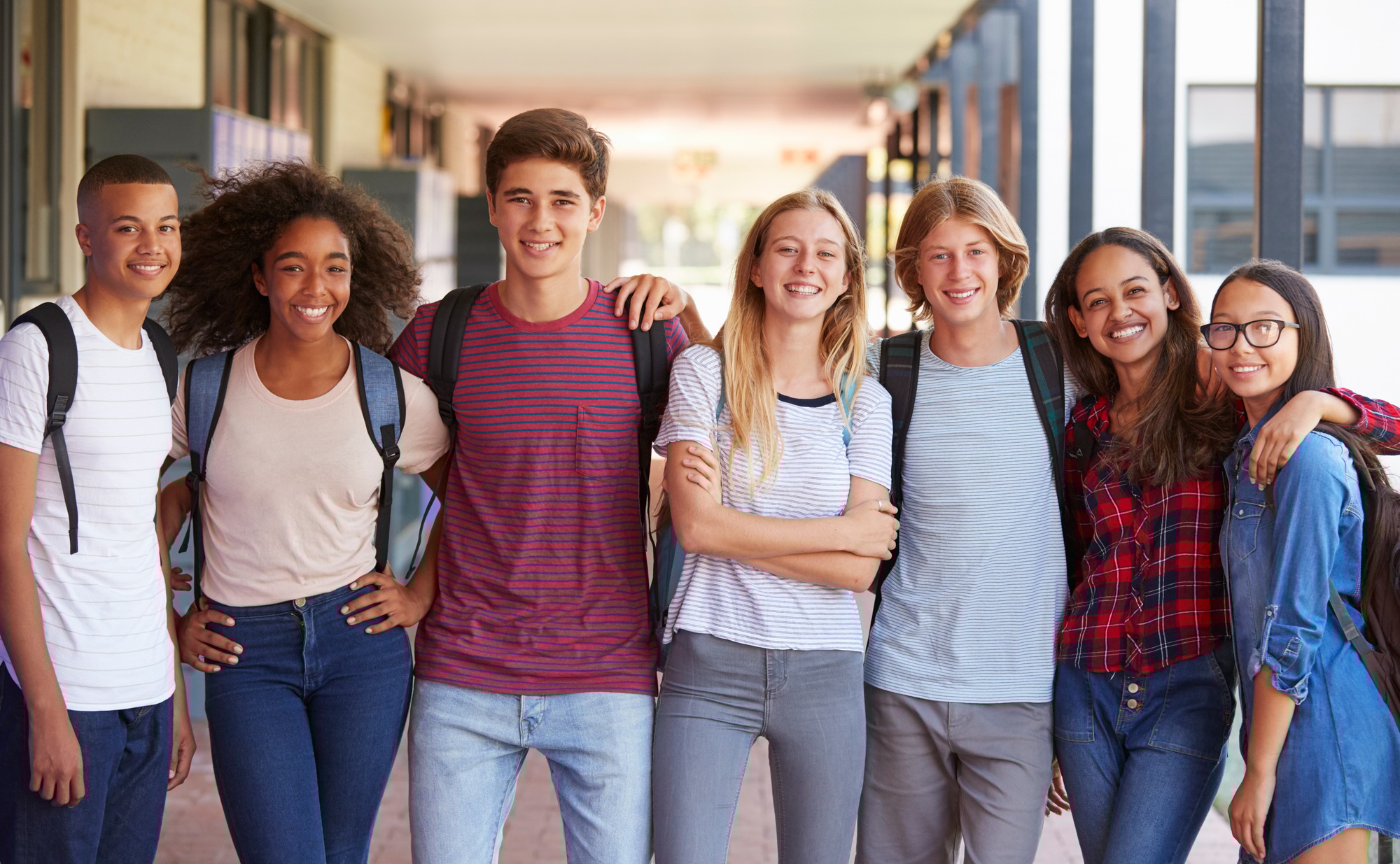 Teenage classmates standing in high school hallway