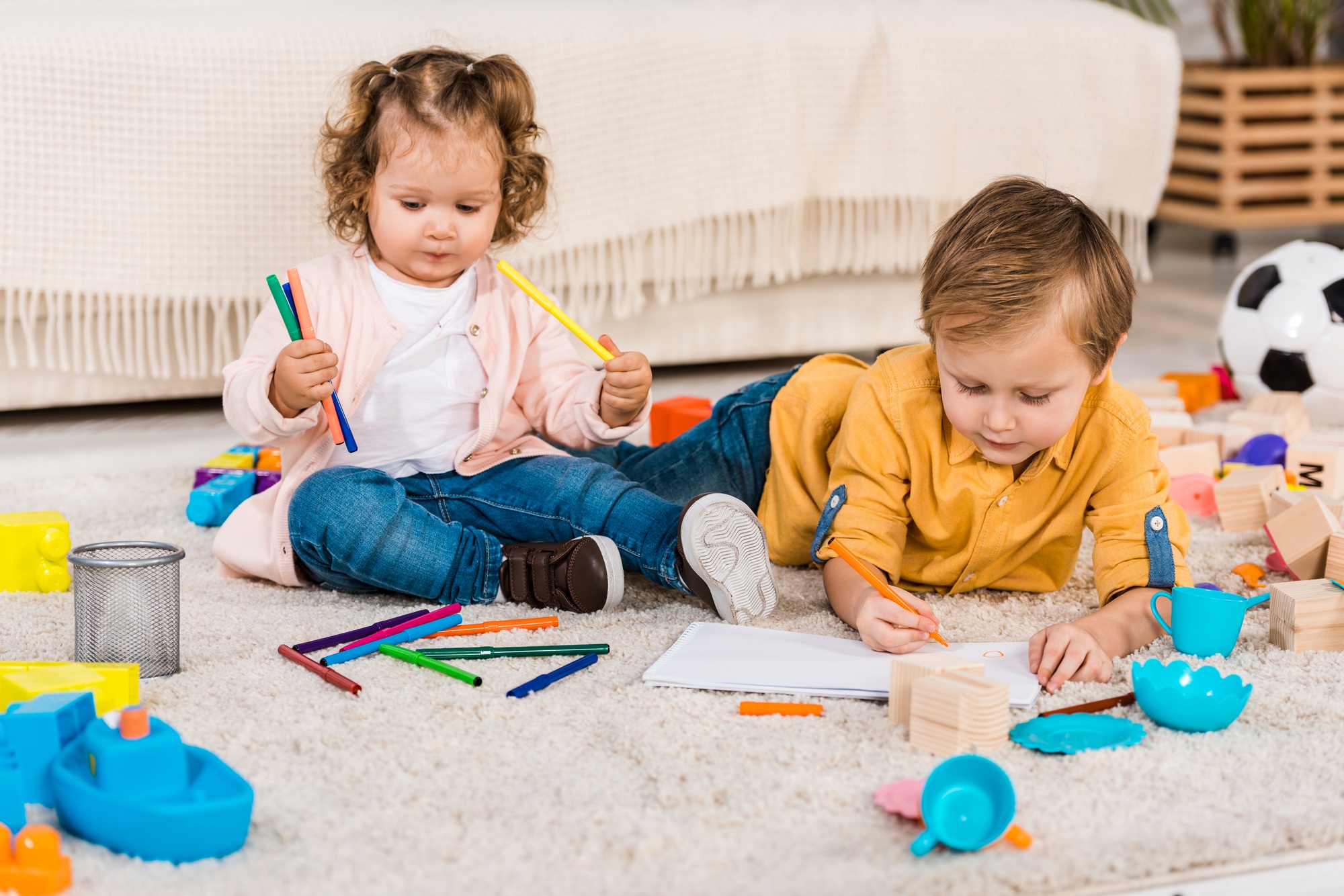 adorable siblings drawing on a floor with colored pencils