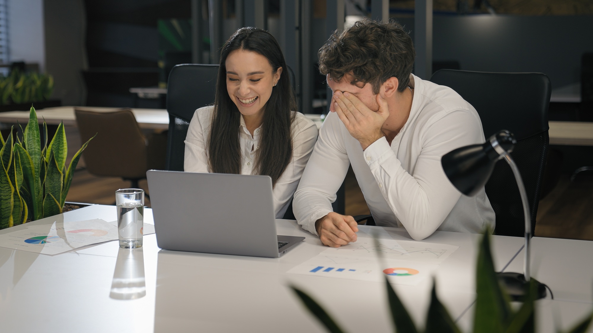 Cheerful Caucasian talking smiling laughing with laptop computer pc in office colleagues male