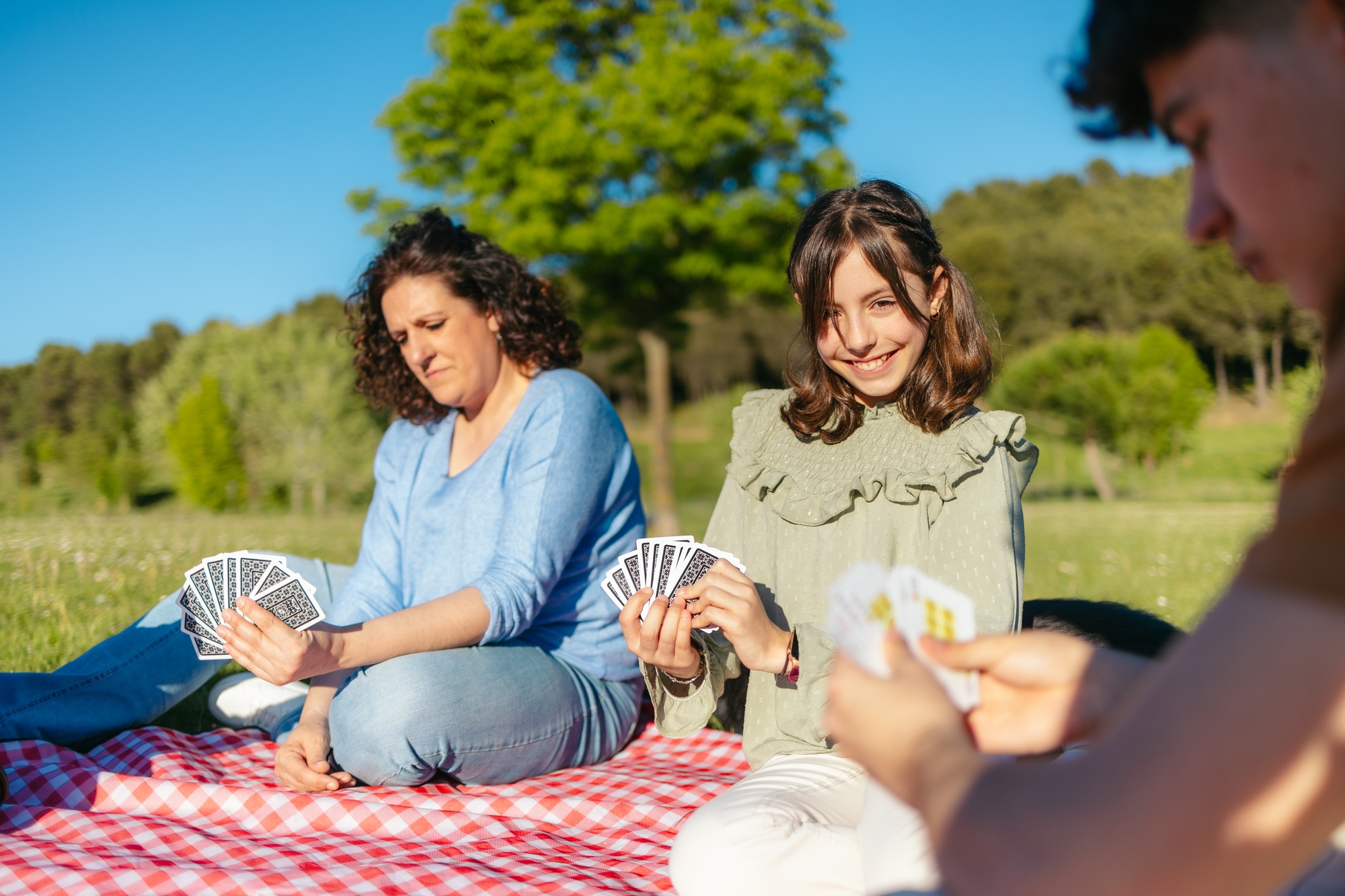 Happy family enjoying a card game during a sunny picnic in a park