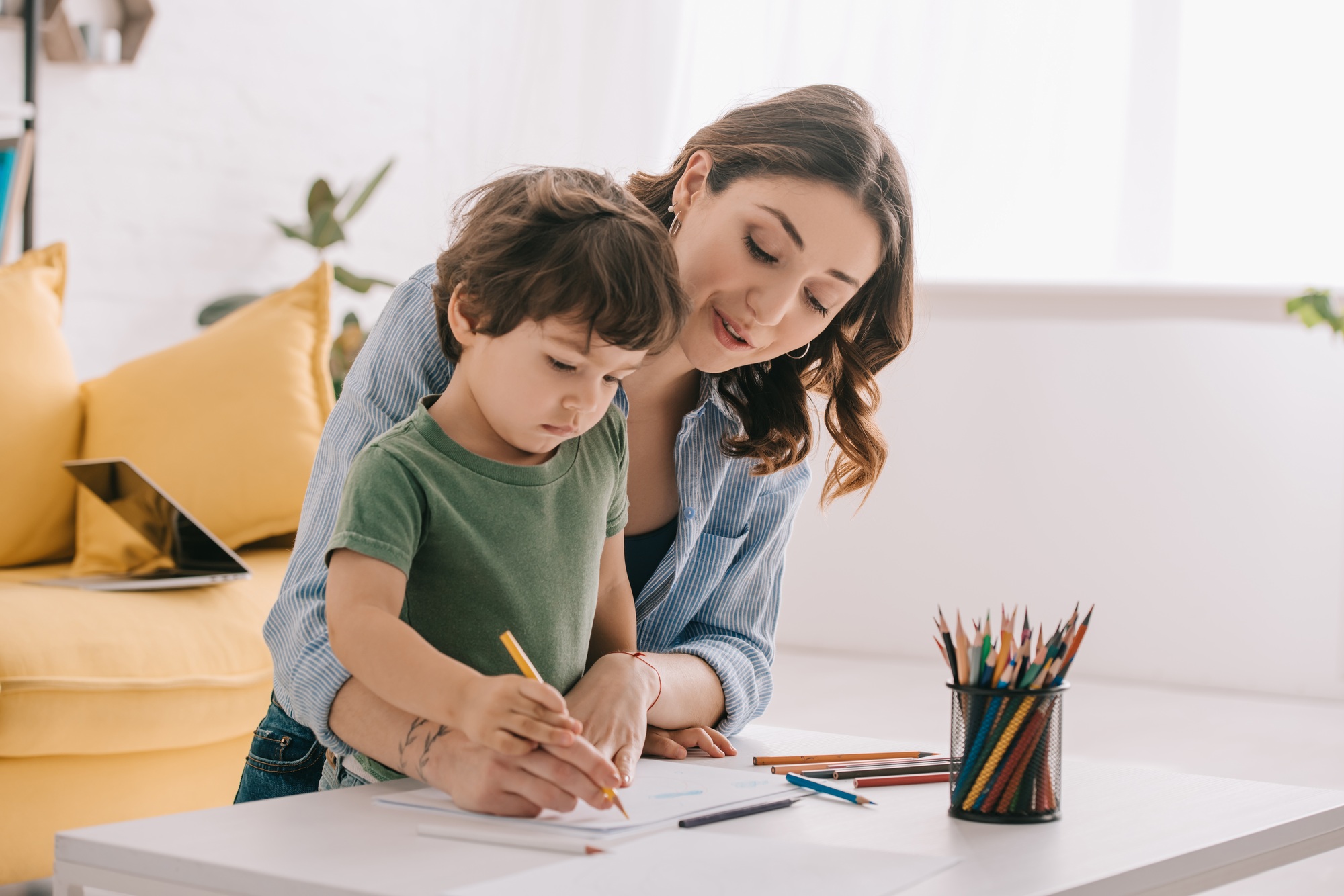 Mother and son drawing with color pencils in living room