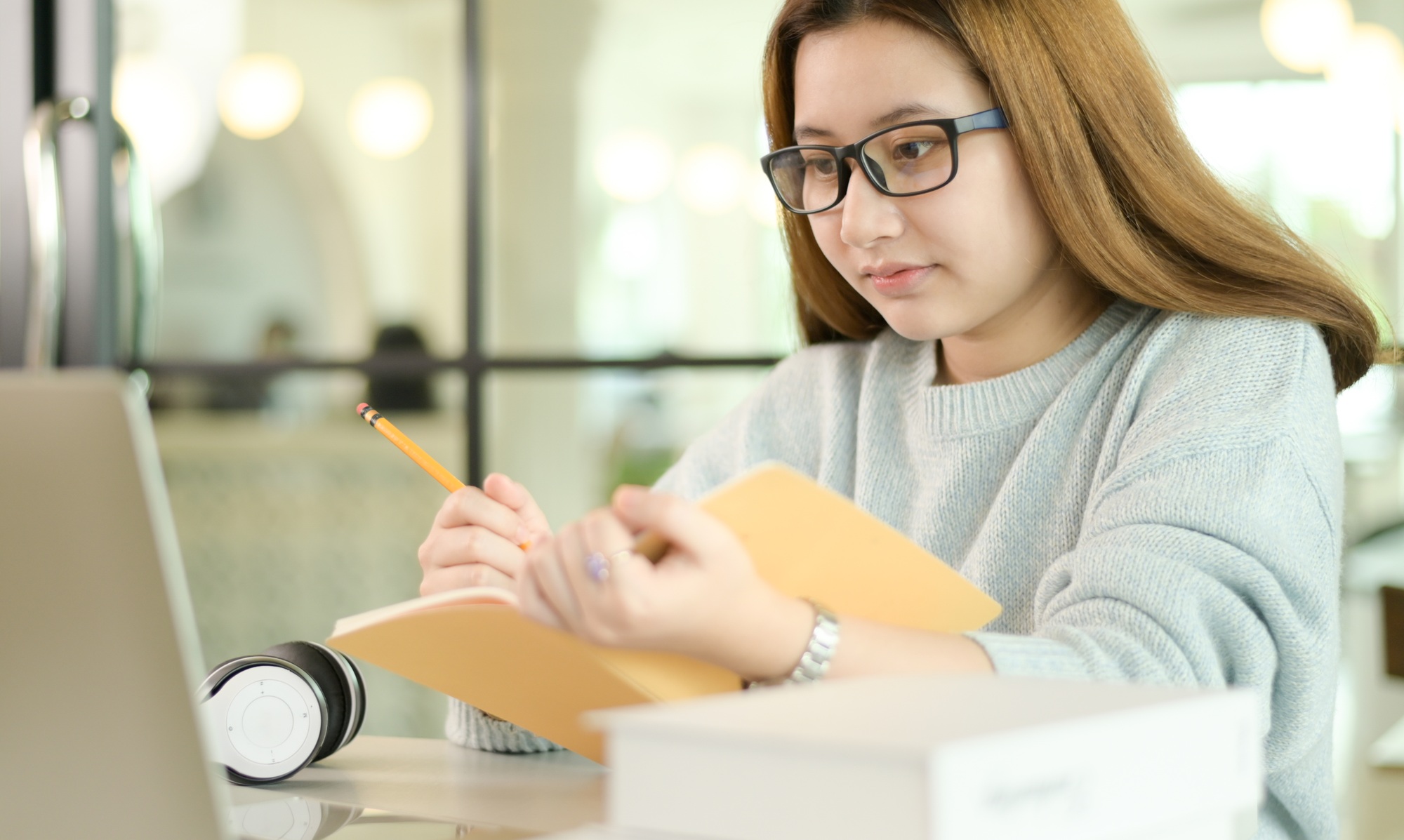 A teenage student taking notes from a laptop diligently.