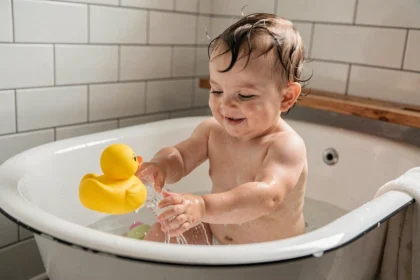 Bébé de 7 mois dans le bain jouant avec un canard en caoutchouc coloré